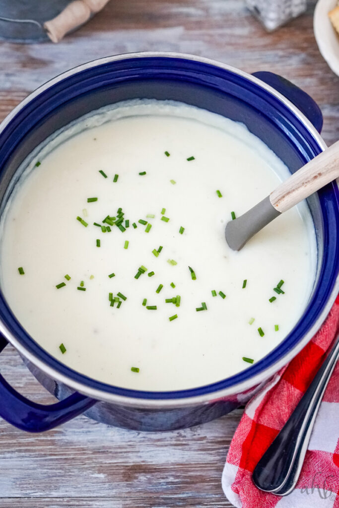 The blue stockpot is filled with creamy 4  ingredient potato soup topped with chopped chives.