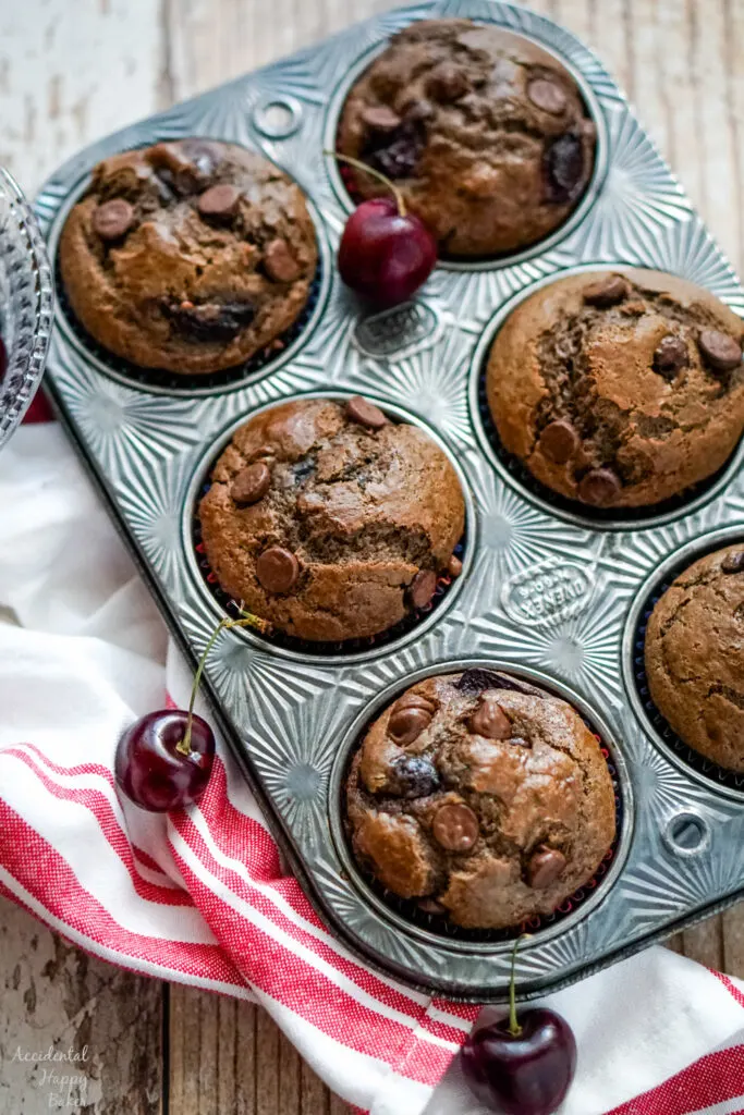 Finished Cherry Chocolate Muffins rest in a muffin tin.