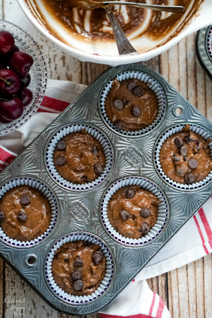 Cherry Chocolate muffin batter is scooped into muffin tins 2/3 full.