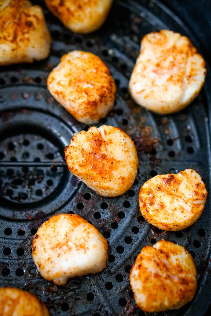 Scallops are spaced apart in an air fryer so that none of them are touching.