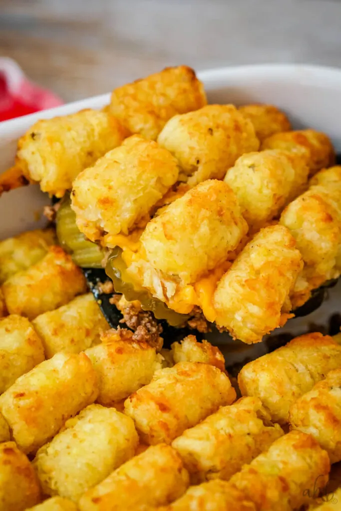 Big Mac Tater Tot casserole is scooped out of the baking dish with a black spatula.