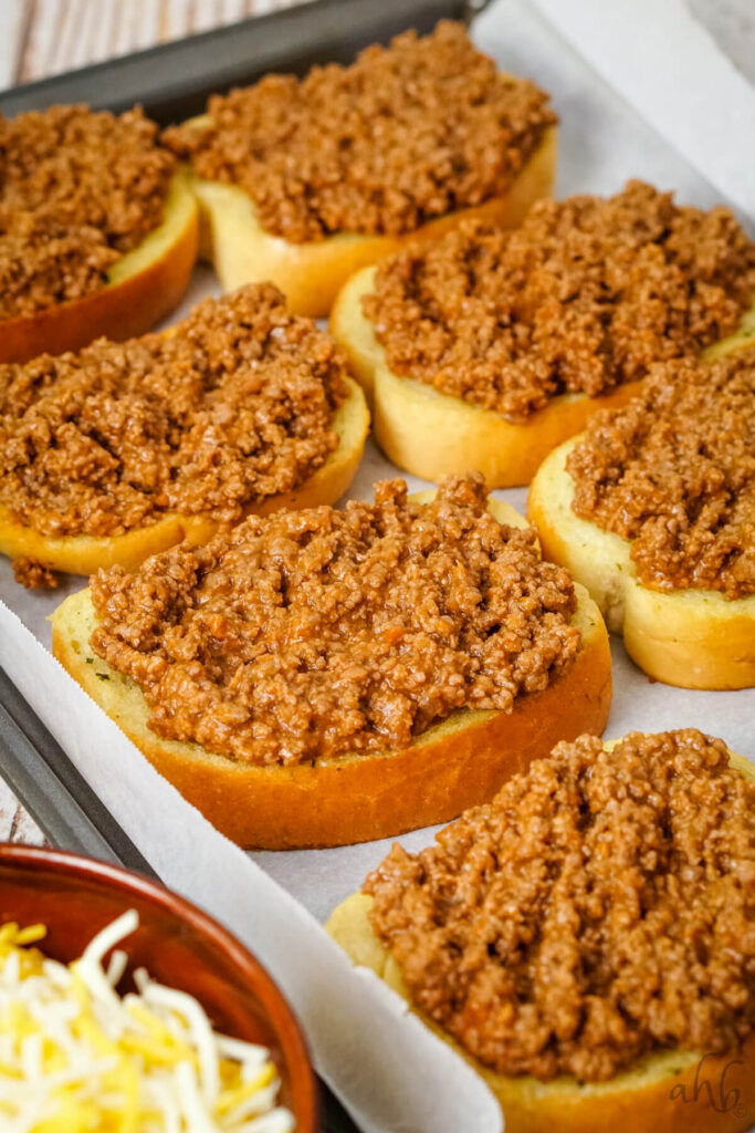 A tray of freshly baked garlic bread heaped with the ground beef mixture.
