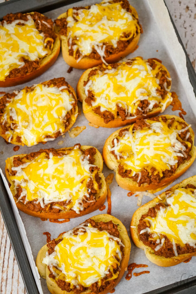 A baking tray of finished Garlic Bread Sloppy Joes topped with melted colby jack cheese.