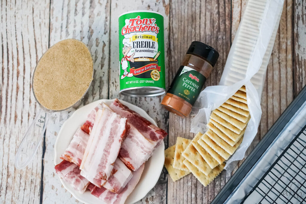 3/4 cup of brown sugar, a plate of raw sliced bacon, Tony Chachere's Creole seasoning, cayenne pepper, and a sleeve of saltine crackers.