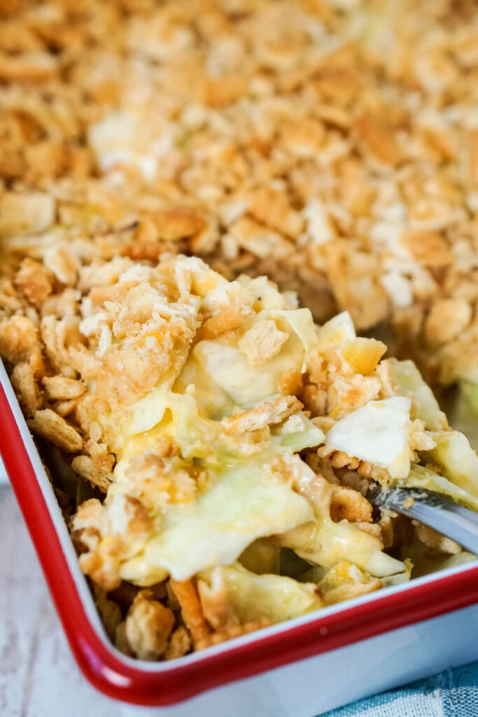 A serving spoon is dipped into a dish of Scalloped Cabbage Casserole.