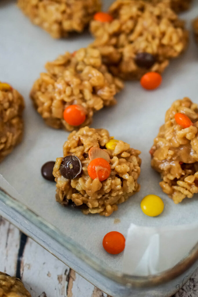 A pan of rice krispies no bake cookies with several reeces pieces laying nearby. 