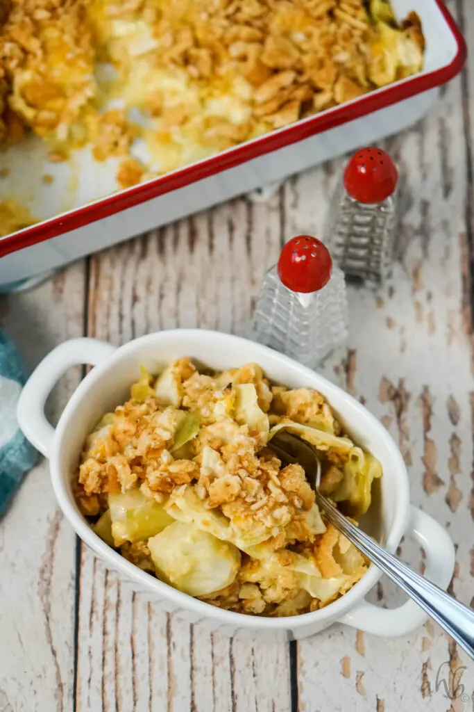 A serving of Scalloped Cabbage Casserole in a white bowl next to salt and pepper shakers.