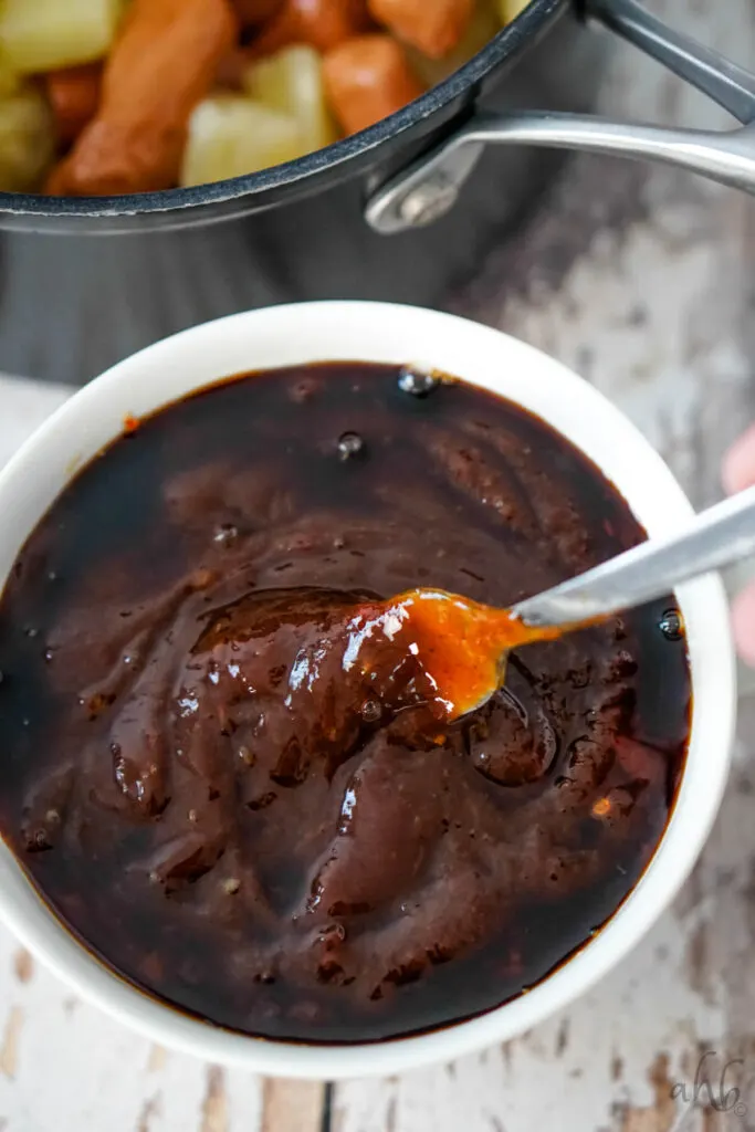 The sweet chili sauce, barbecue sauce, and soy sauce are stirred together with a fork.