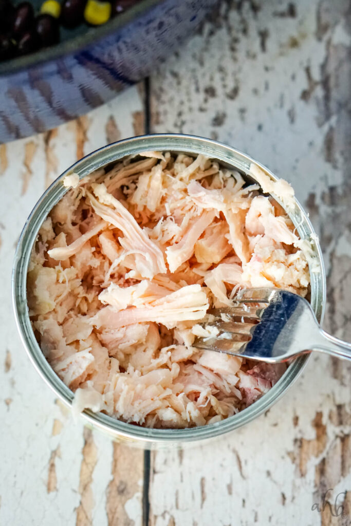 A can of Chunked chicken breast that has been shredded with a fork. 