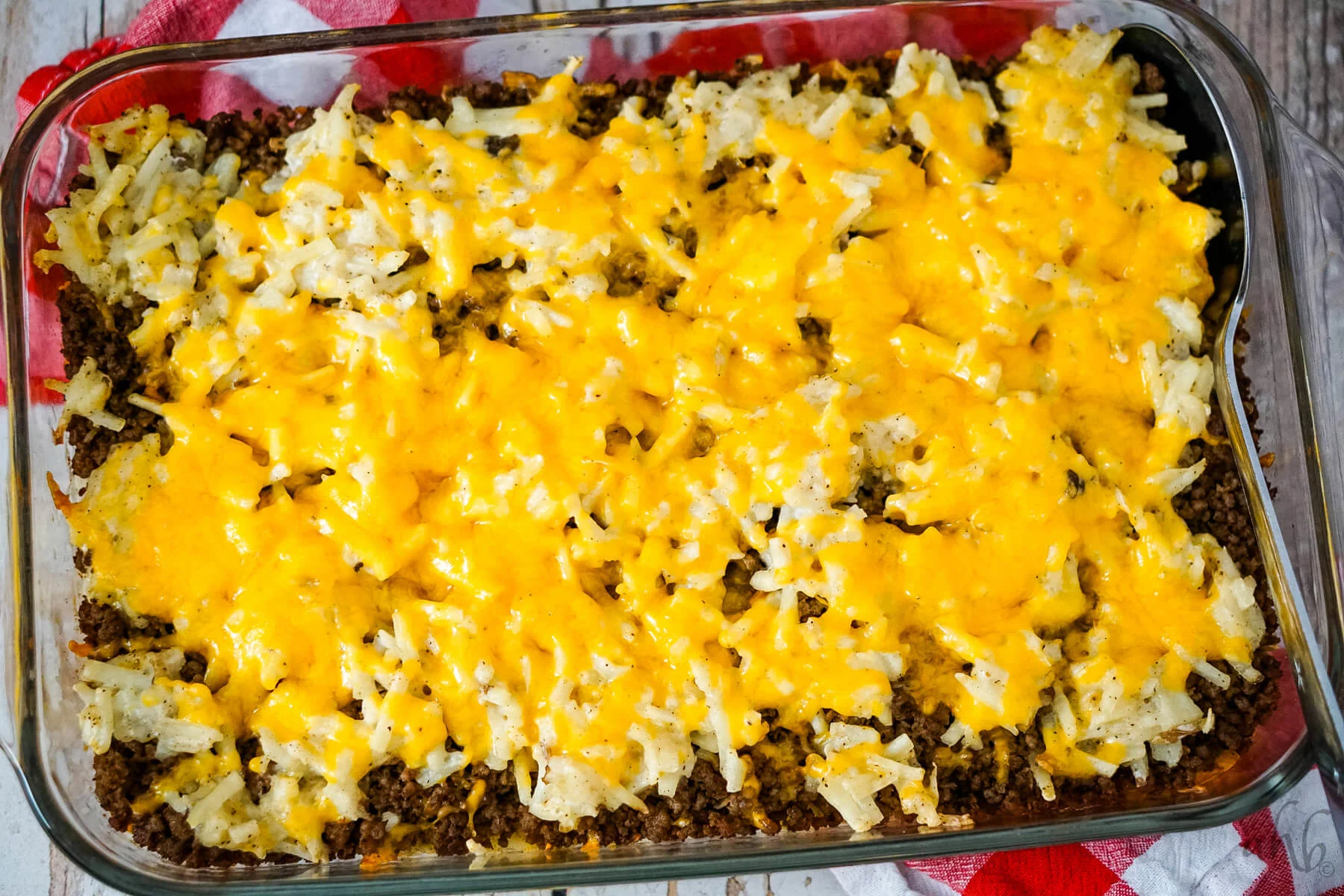 A pan of Hamburger Hashbrown Casserole with a spoon to one side. 