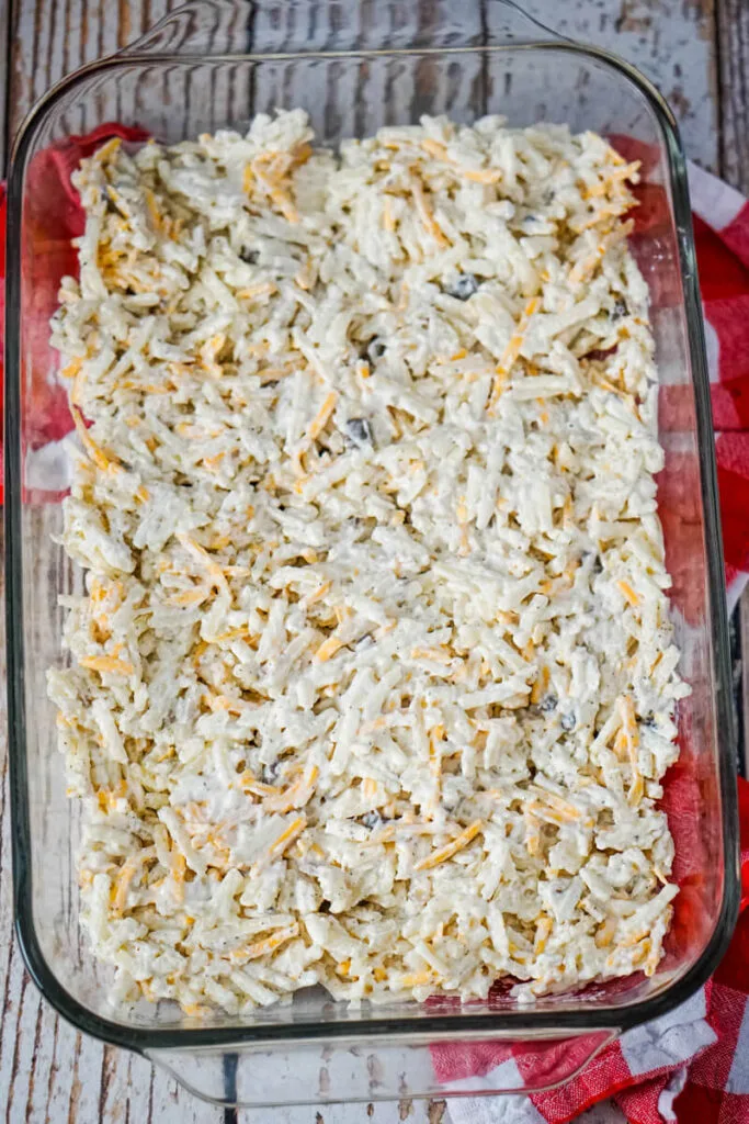 A layer of the potato mix is spread evenly in a 9x13 casserole dish.