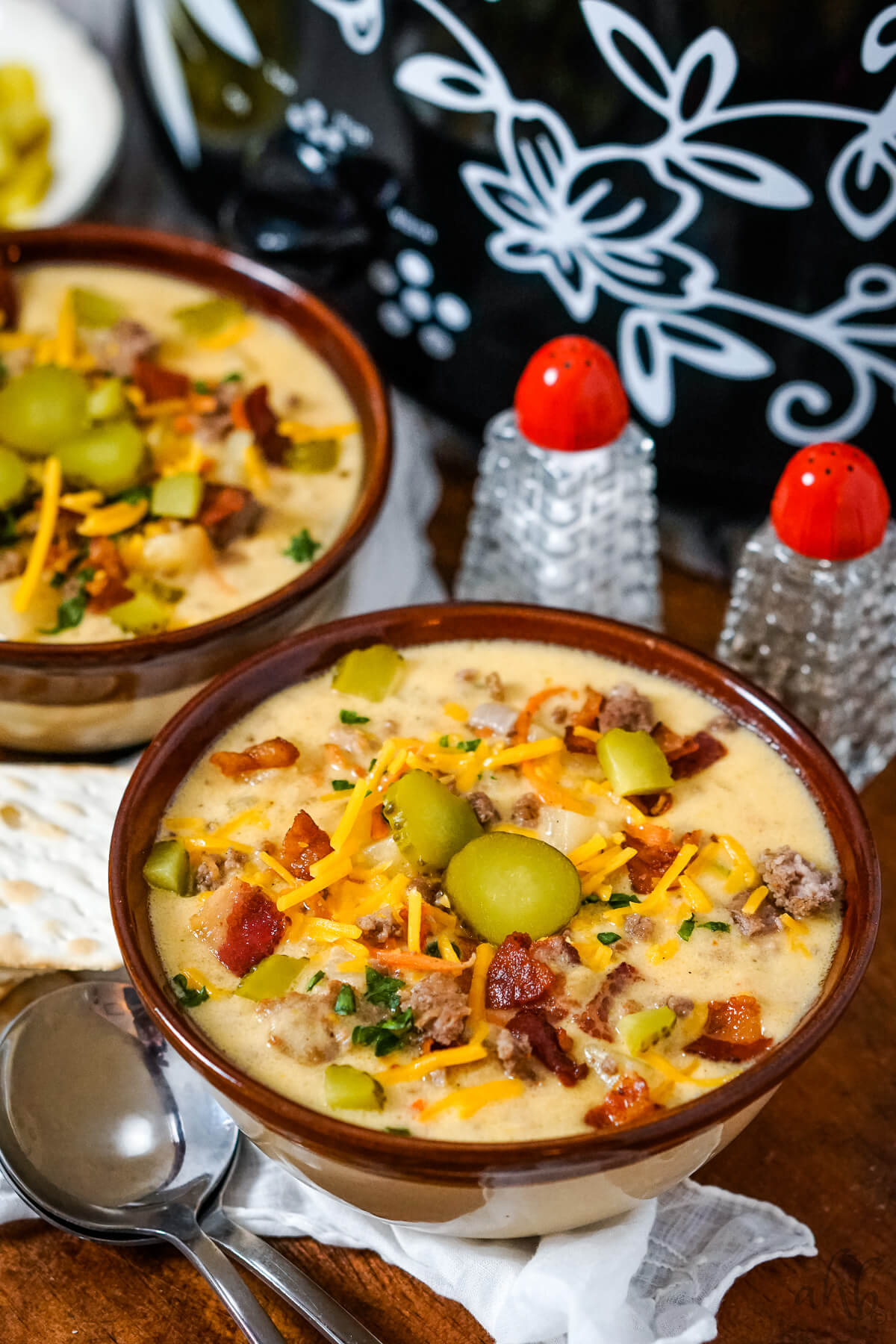 Two bowls of slow cooker bacon cheeseburger soup on a serving tray next to a slow cooker.