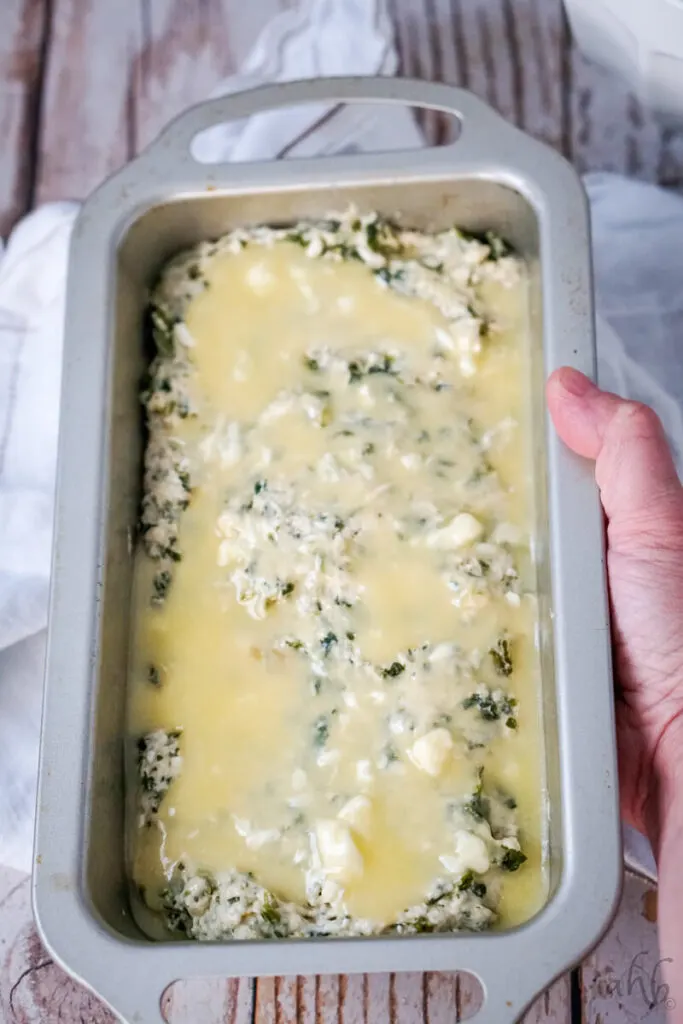 The mixture is added to a bread pan, and melted butter is poured on top.