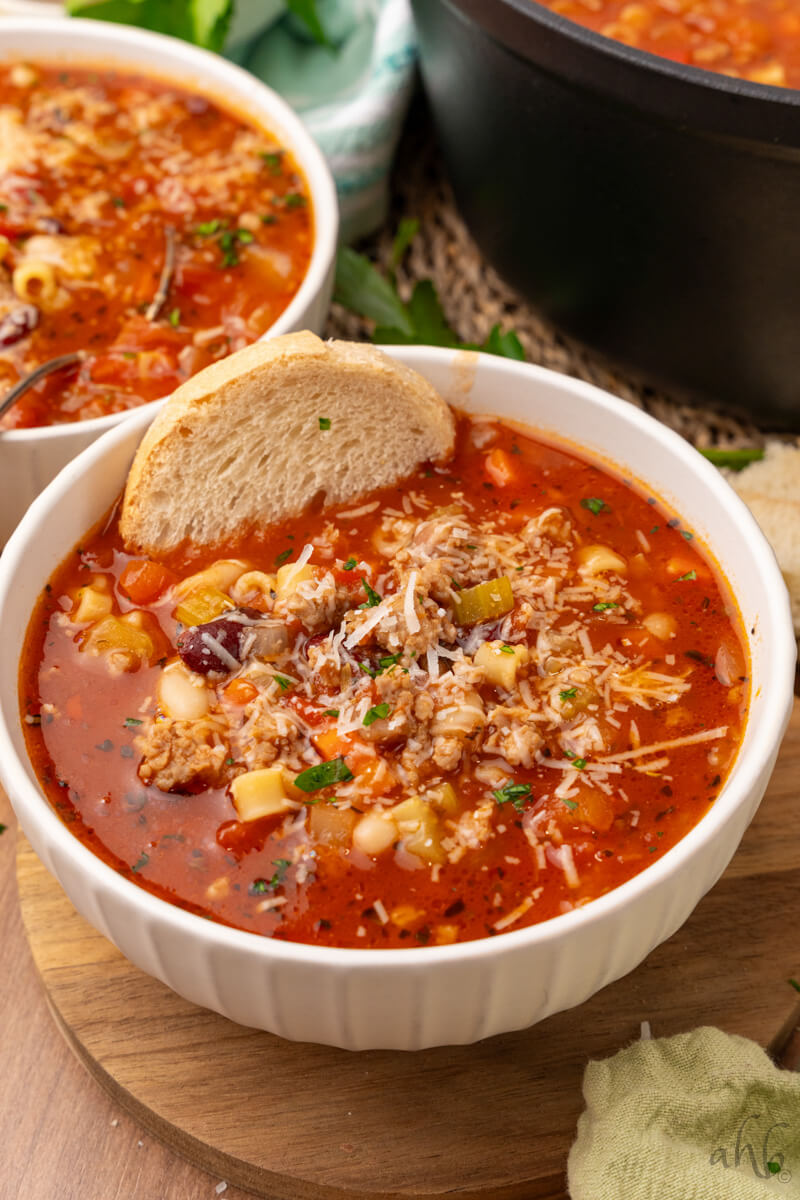 Two bowls of Pasta Fagioli are served with a slice of bread.