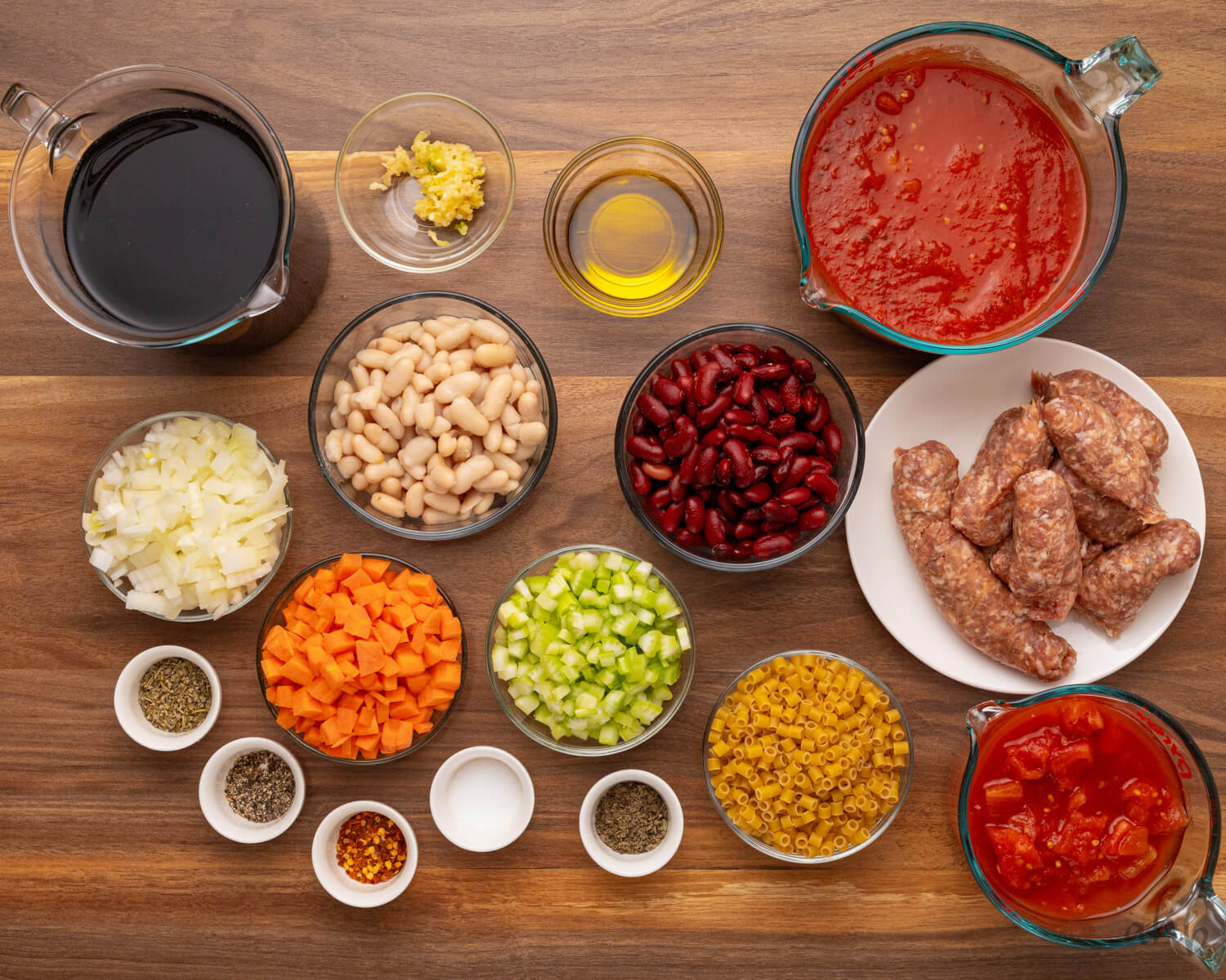 The ingredients of pasta fagioli are measured out in dishes and are ready to be combined.