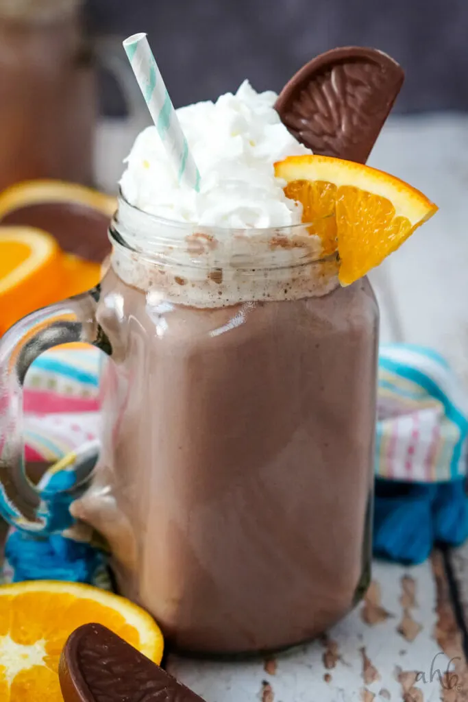 A close up image of a mug of orange hot chocolate with a colorful striped napkin in the background. 