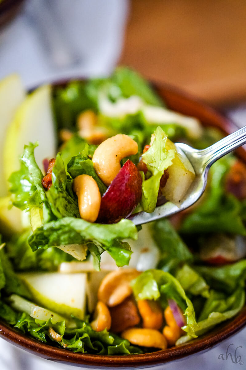 A forkful of the Cashew Nut Salad is taken from the brown bowl.