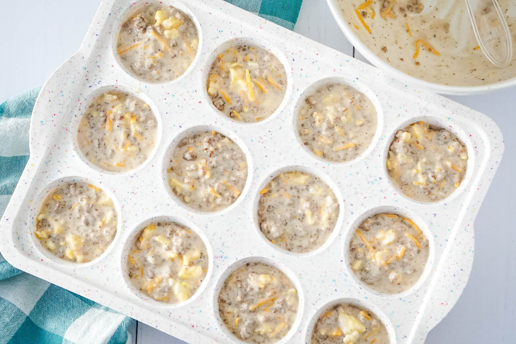 The muffin mixture is added to the greased muffin tin.