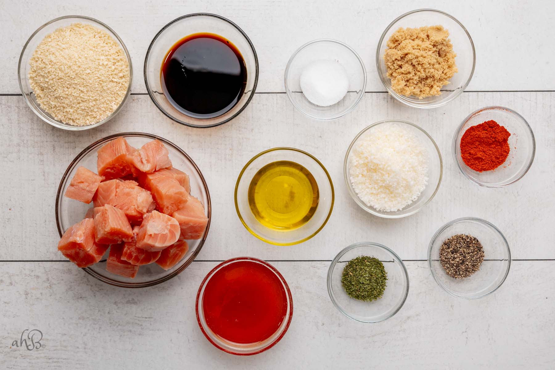 the ingredients for salmon bites are separated into clear glass bowls.